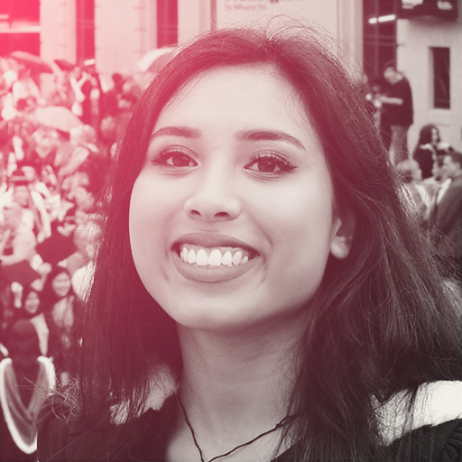 Aleisha is pictured smiling at her university graduation parade, on the steps of Civic Square. She is wearing a korowai with blue, green, black and white detailing atop her graduation gown.